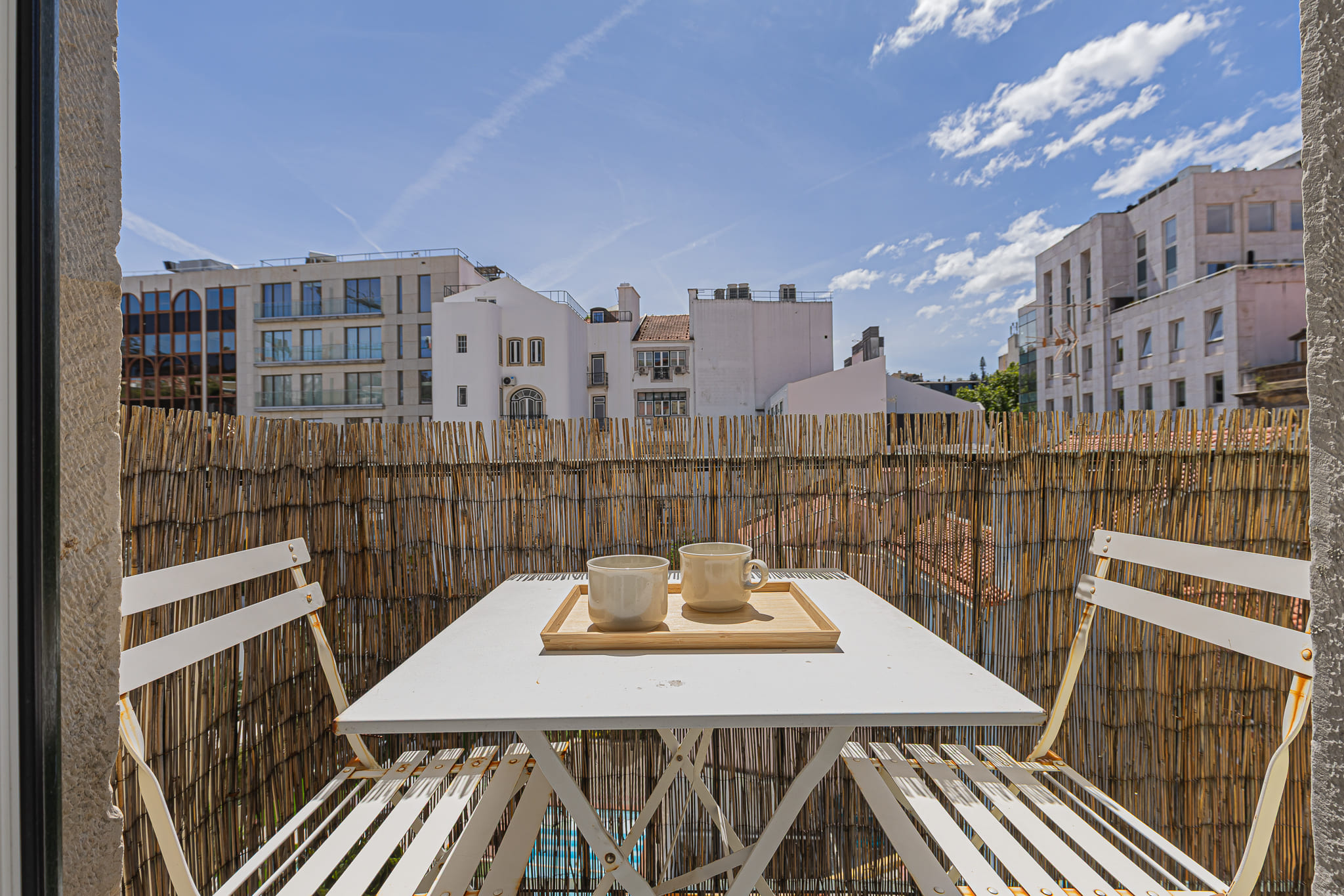 Varanda com mesa e chávenas — céu azul de Lisboa