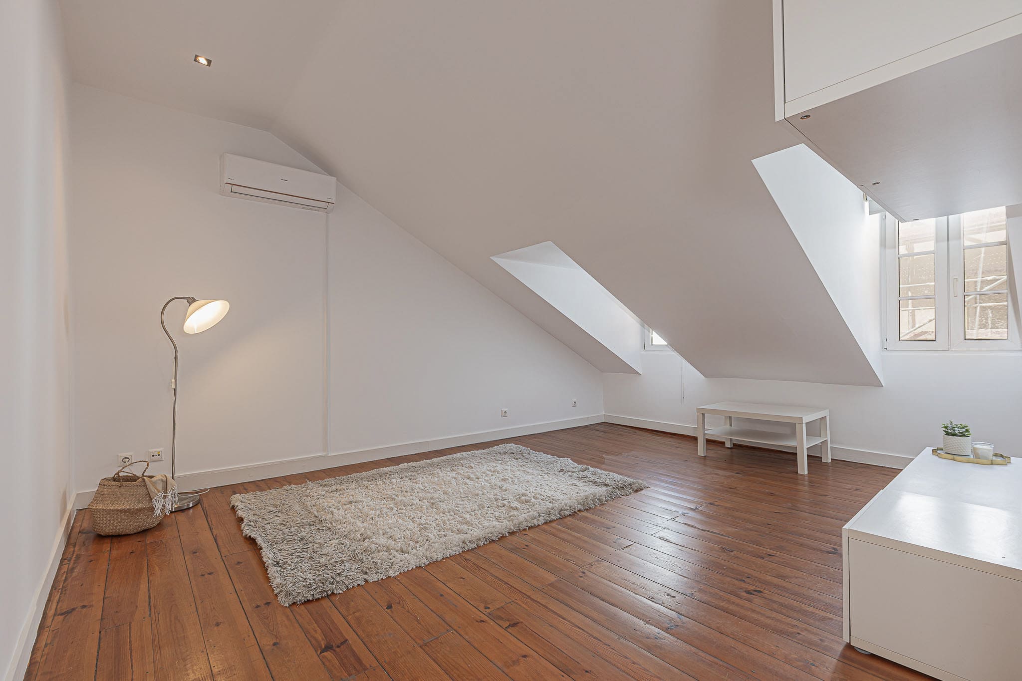 Sala luminosa com claraboias e soalho de madeira